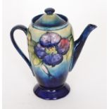 A Moorcroft Clematis pattern coffee pot decorated with tubelined flowers and foliage to a blue