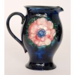 A Moorcroft Anemone pattern water jug decorated with two tonal flower heads against a blue ground,