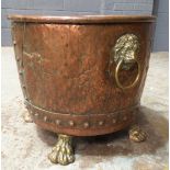 An early 20th Century copper log bin, raised to brass lion's paw feet, height 36cm. A/F.