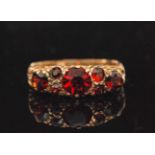 A 9ct seven stone garnet ring claw set stones to a pierced head and detailed shoulders, ring size N.