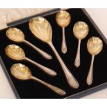 A cased set of seven hallmarked dessert spoons each terminating in panelled gilt bowls,