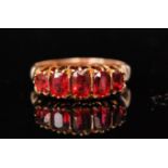 An early 20th Century 9ct hallmarked rose gold graduated five stone ruby ring, claw set stones,