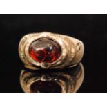 A 10ct garnet ring, the oval cabochon garnet collar set within a shaped head to tapering band,