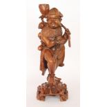 A carved Oriental hardwood lamp base in the form of a man holding a large lotus flower and a bough