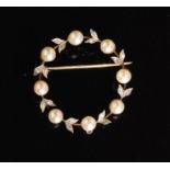 A diamond and pearl circular wreath brooch set with eight cultured pearls each spaced by rose cut