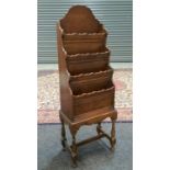 A mid 20th Century oak waterfall magazine rack on turned baluster legs and stretchers,