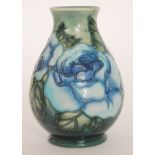 A Moorcroft Pottery vase decorated with large blue flowers against a tonal green ground,