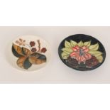 Two Moorcroft Pottery coasters, the first decorated with brambles, the second with flowers,