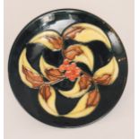 A Moorcroft Pottery shallow dish decorated with leaves and red berries, impressed mark,