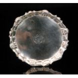 A George II hallmarked silver waiter of circular outline with shell and scroll border,