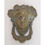 A brass Art Nouveau style door knocker in the form of a maiden wearing a fruiting vine headdress,