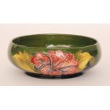 A Moorcroft footed bowl decorated in the Hibiscus pattern against a graduated green to blue ground,