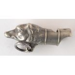 A white metal dog whistle the mouthpiece terminating in the study of a dog's head, length 4.5cm.