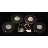 Four contemporary circular coasters, each with silver panels within a grey marble border,