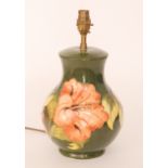 A Moorcroft lamp base decorated in the Hibiscus pattern with coral flowers against a green ground,