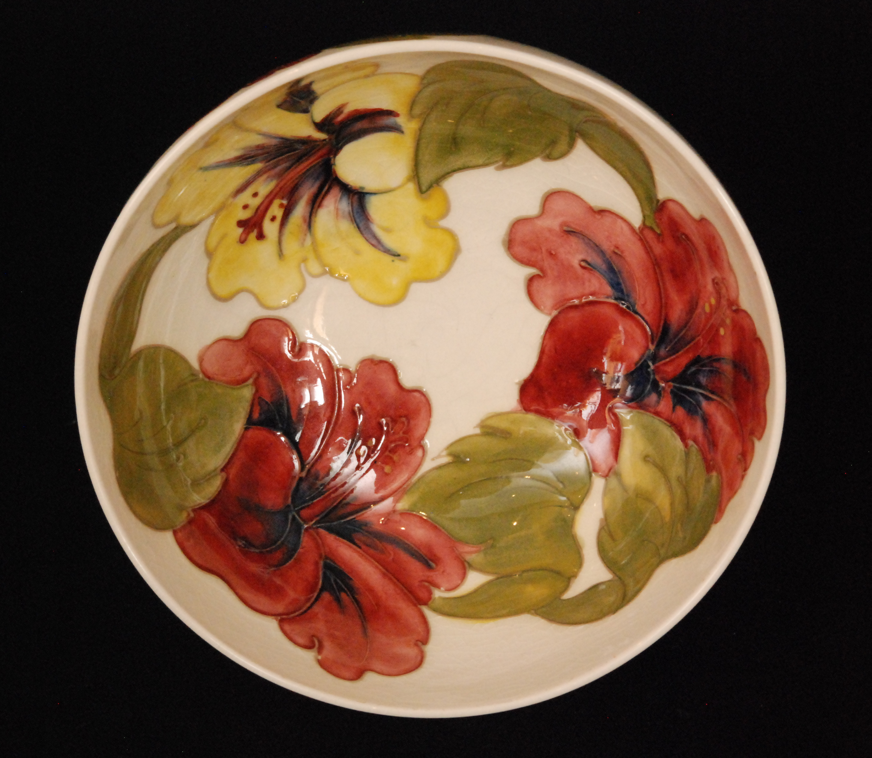 A Moorcroft footed bowl decorated in the Hibiscus pattern against a white glazed ground,