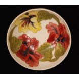 A Moorcroft footed bowl decorated in the Hibiscus pattern against a white glazed ground,