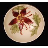 A Moorcroft small footed circular bowl decorated in the Columbine pattern to a white ground,