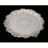 An early 20th Century hallmarked silver waiter with central foliate decoration within scroll border,