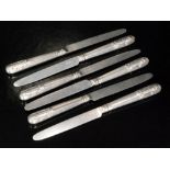 A set of six hallmarked silver dessert knives with shell and reed handles below plain silver blades,