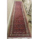 A long crimson ground hand knotted Iranian Runner, 401cms x 77cms (13'2" x 2'5").