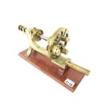 Watchmaker's brass mandrel mounted on a mahogany stand, stamped J&T Jones, Prescot, 12" wide