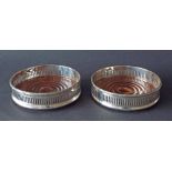 Pair of Georgian style silver rimmed wine coasters, with geometric pierced borders and turned