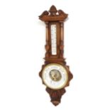 Oak cased aneroid barometer/ thermometer, the 8" white chapter ring enclosing a skeletonised centre,
