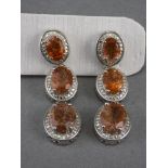 Tanzanian Sunstone Triple Drop Earrings, each earring having three graduated oval cut sunstones, a