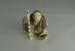 Japanese - Early 20th Century Carved Ivory Netsuke of a Crouching Figure Holding a Staff. 1.