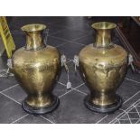 Pair Of Large Brass Vases, With Mask And Ring Handles, Raised On Circular Black Plinths, 24'' In