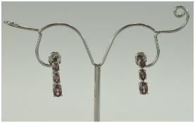 Malaya Garnet Drop Earrings, each comprising three oval cut stones of the unusual dark rose pink