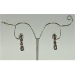 Malaya Garnet Drop Earrings, each comprising three oval cut stones of the unusual dark rose pink