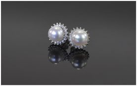 Pair of Ladies 9 Carat White Gold Stud Earrings central pearl surrounded by round cut diamonds.