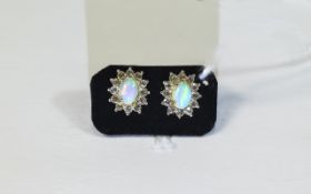 Natural Opal and White Topaz Stud Earrings, each earring comprising an oval cut Ethiopian opal