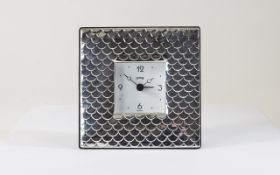 A Modern Silver Table Clock with Overlapping Shell Design to Front, Mahogany Back, Chrome Supports.