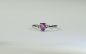 9 Carat White Gold Dress Ring central oval pink sapphire between 2 round cut diamonds.