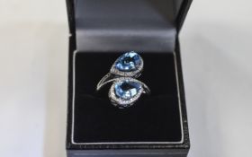 Swiss Blue Topaz Crossover Ring, two pear cut stones, each of 2.25cts, set in a rhodium vermeil