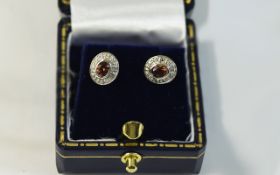 Pair of Ladies Diamond and Ruby Stud Earrings. Central ruby surrounded by round cut diamonds.