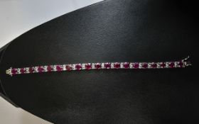 Ruby and White Topaz Tennis Bracelet, 42cts of round cut rubies highlighted by pairs of small