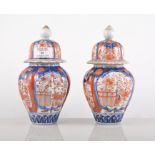 Pair of Imari fluted baluster vases with domed covers, floral decoration in a typical palette,