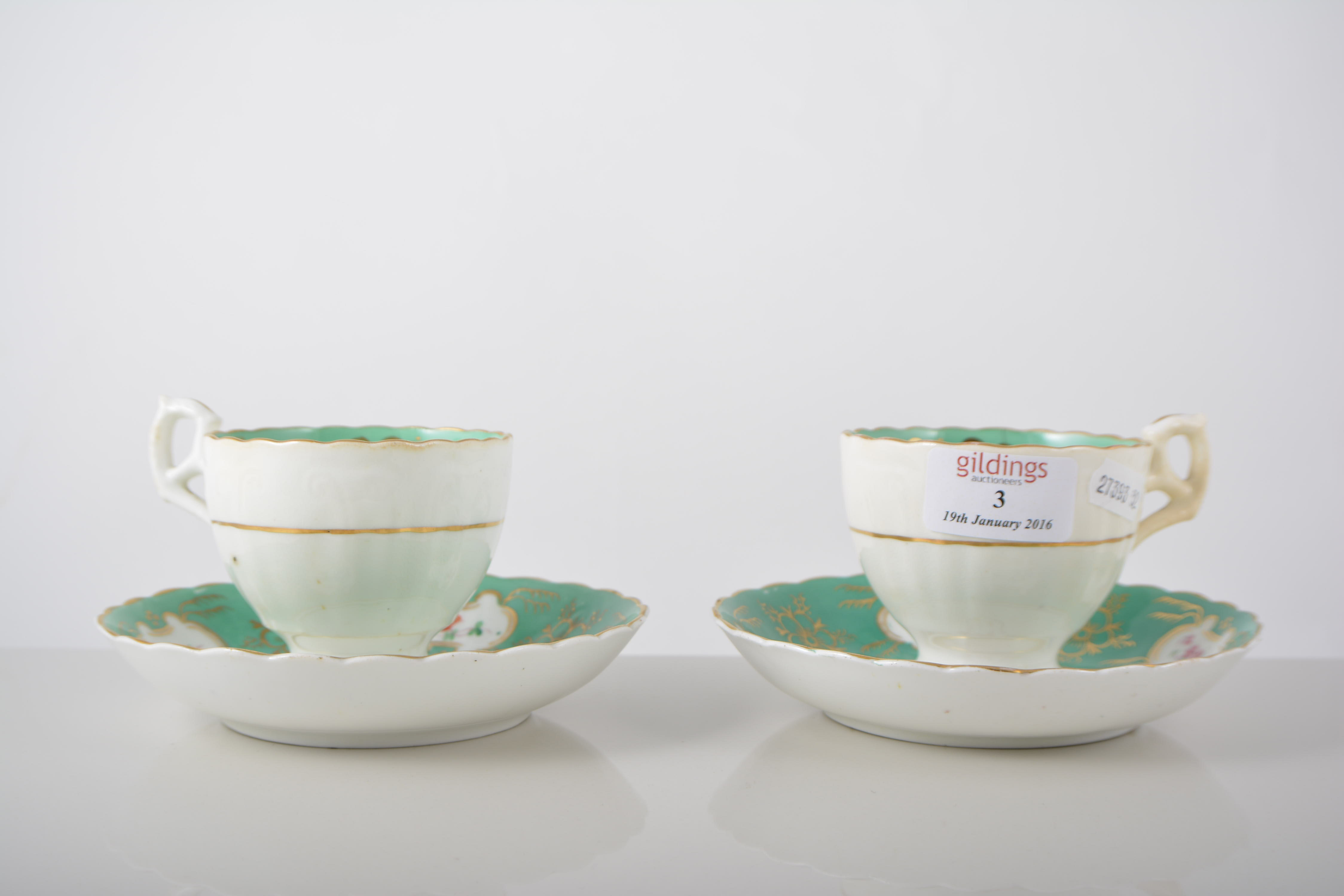 Pair of Victorian cups and saucers, green and gilt borders, painted with floral sprays,