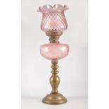 Brass oil lamp, pink tinted moulded reservoir, shade, height overall 59cm.