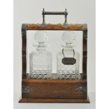 Victorian oak tantalus, silver plated mounts, containing two decanters, width 26cms, with key.
