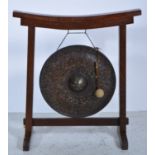 Eastern circular metal gong, diameter 46cm, with mallet mounted on a n oak frame, width 73cm,