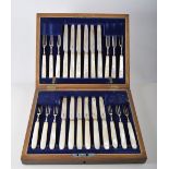 Fitted oak canteen containing twelve silver dessert knives and forks with mother of pearl handles,