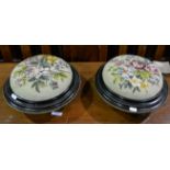 Pair of ebonised Victorian circular footstools with needlepoint pads, diameter 32cms.