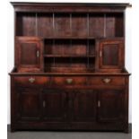 A George III oak dresser, moulded cornice, the top with fixed shelves and cupboards,