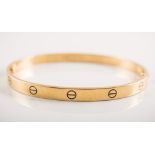 Cartier - An 18 carat yellow gold "Love Bangle" decorated with a number of screw head motifs.