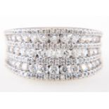 A diamond set dress ring, a wide concave white metal mount claw set with seven rows of diamonds,